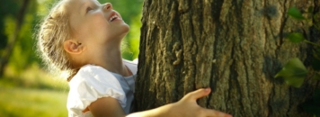 Bambina nella natura abbraccia un albero