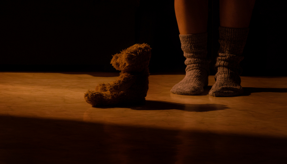 pedi di bambino accanto a orsacchiotto nel buio