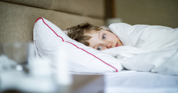 bambino a letto ammalato guarda le medicine