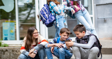 adolescenti amici ridono guardando lo smartphone