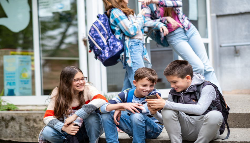 adolescenti amici ridono guardando lo smartphone