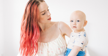 Donna con capelli tinti tiene in braccio il suo bambino