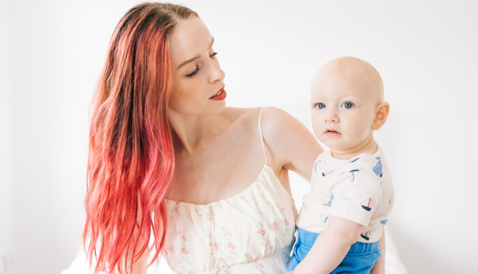 Donna con capelli tinti tiene in braccio il suo bambino